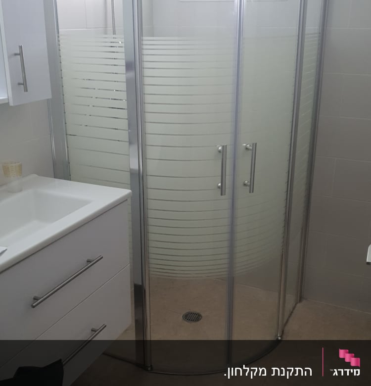 מקלחון זכוכית עם דלתות מתכת בחדר אמבטיה